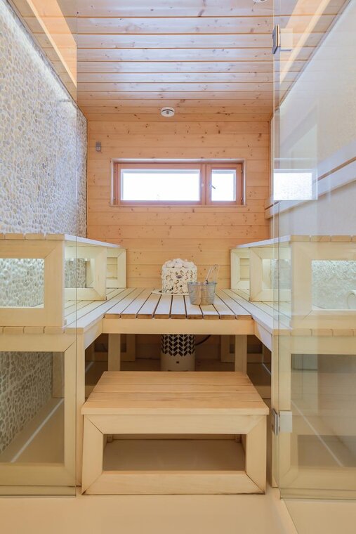 Vaalea sauna haapalauteilla ja luonnonkiviseinällä