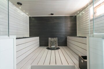 Valkoinen moderni sauna mustalla päätyseinällä
