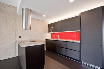 Mustaa, punaista ja betonia loft-kodin keittiössä