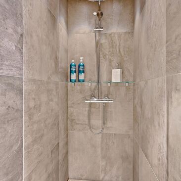 Suuri sadesuihku ja betonimaiset laatat kylpyhuoneessa