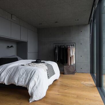 Tyylikkäitä pintoja betonitalon harmaassa makuuhuoneessa