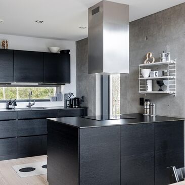 Musta moderni keittiö betoniseinineen